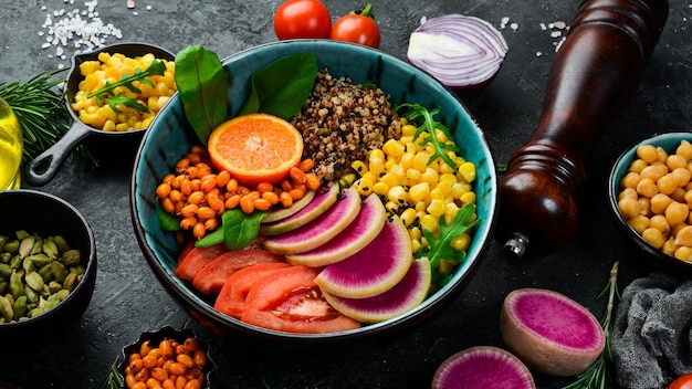 Buddha-Schüssel Quinoa Spinat Mais Tomaten und Wassermelone Rettich Sanddorn Gesundes vegetarisches Essen Super Food Draufsicht Auf einem Steinhintergrund