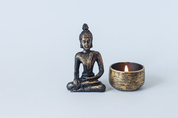 Buddha-Statue auf Altar mit brennender Kerze. Meditation, Buddhismus und Erleuchtungskonzept