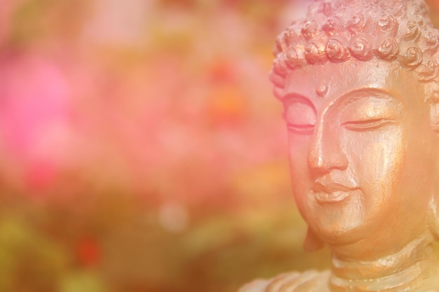 Foto buddha-statue im garten mit verschwommenen blumen im hintergrund