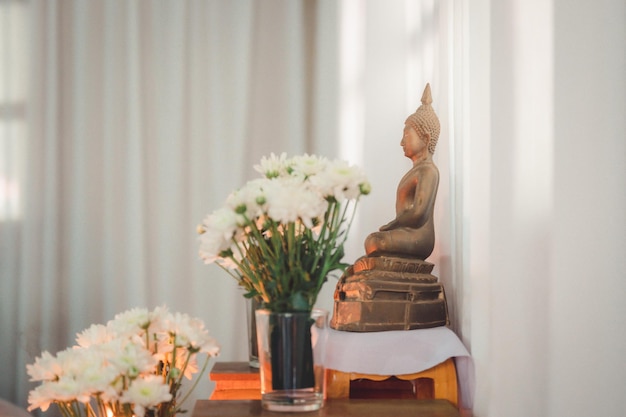 Buddha-Statue mit Blumen und weißem Hintergrund