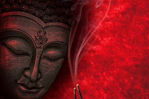 Foto buddha-statue mit rotem hintergrund und weihrauch