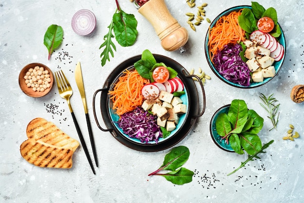 Buddhas vegane Schüssel Tofu-Käse Spinatkohl Radieschen und Karotten Das Konzept der gesunden Ernährung Auf einem Steinhintergrund Ansicht von oben