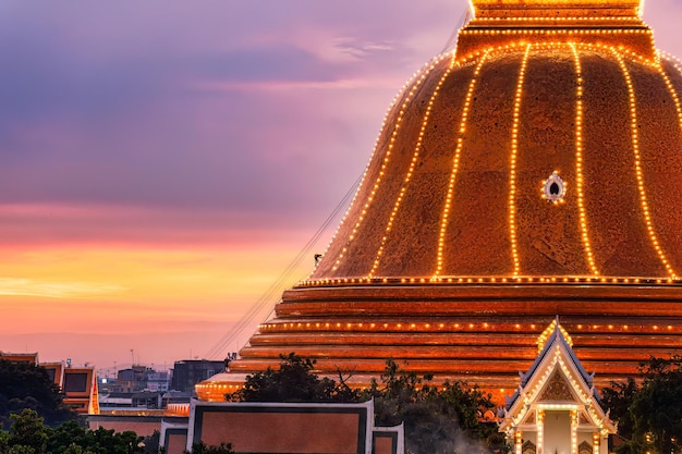 Buddhisten klettern auf die leichte Dekoration der goldenen Pagode Phra Pathom Chedi am Sonnenuntergang im jährlichen Fest in Nakhon Pathom