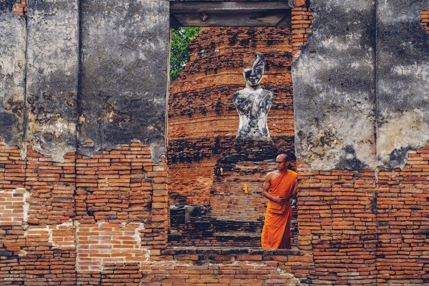 Buddhistischer Mönch, der vor Ruine altem Wat R steht