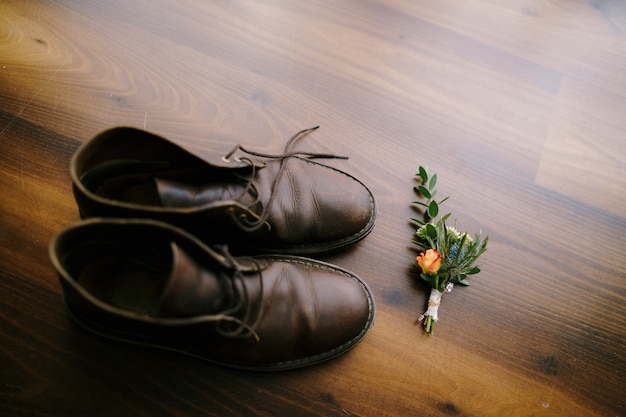 Un budier con una rosa para el novio y zapatos de hombre.