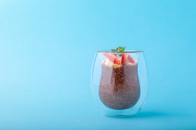 Budín de chía de chocolate decorado con fresa sobre fondo azul