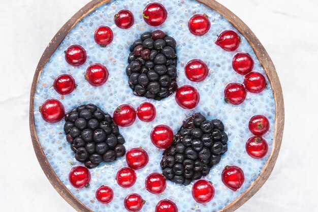 Budín de semillas de chía azul con moras y bayas de grosella roja en un tazón