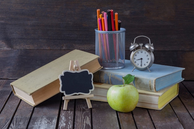 Foto bücher, buntstifte, wecker, grüner apfel und eine schreibtafel