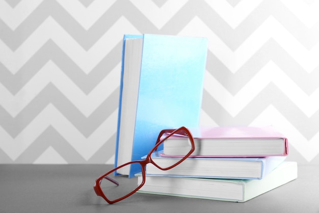 Bücher und Brillen auf grauem Tisch gegen Verzierungswand