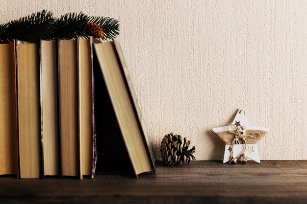 Bücher und ein Weihnachtsbaum mit Kegeln und eine Sterndekoration auf einem alten hölzernen Regal.