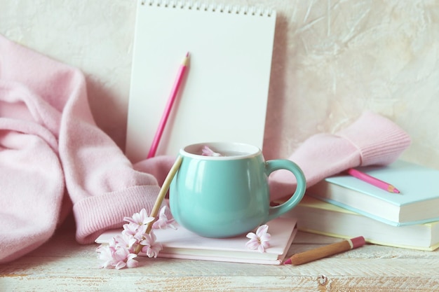 Bücher und Notizbücher, rosafarbene Hyazinthenblumen, rosa Kaschmirpullover, eine Tasse Wasser