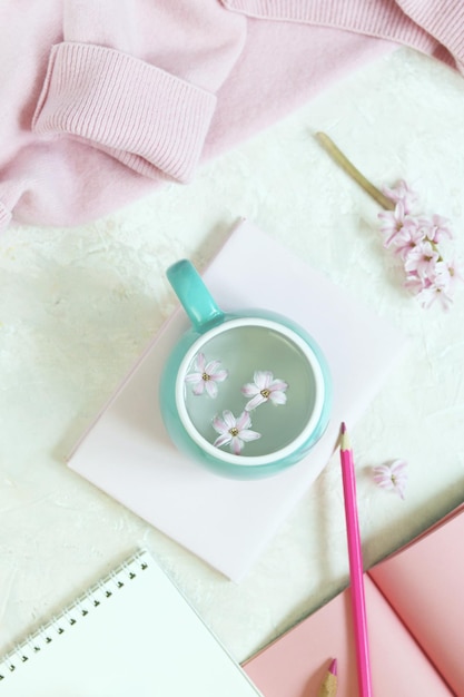 Bücher und Notizbücher, rosafarbene Hyazinthenblumen, rosa Kaschmirpullover, eine Tasse Wasser