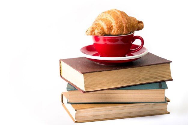 Bücher und rote Tasse Kaffee mit Croissant auf weißem Hintergrund