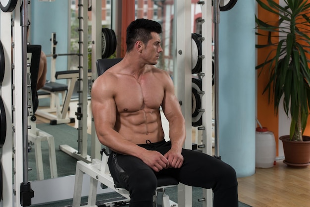 Buen aspecto y atractivo joven con cuerpo musculoso relajante en el gimnasio