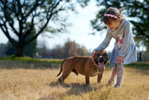 Buen chico Disparo de una niña jugando con su perro en un parque