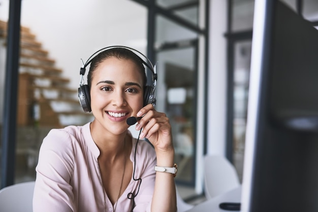 Buen día, ¿cómo puedo ser de servicio? Retrato de una alegre mujer de negocios hablando con un cliente usando un auricular mientras mira la cámara.