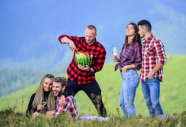 Buen día, hombres y mujeres felices, amigos, comen sandía, amistad, picnic romántico en un campamento de turismo, vacaciones de verano, un grupo de personas pasan tiempo libre juntos, acampan en familia, hacen senderismo, aventura.