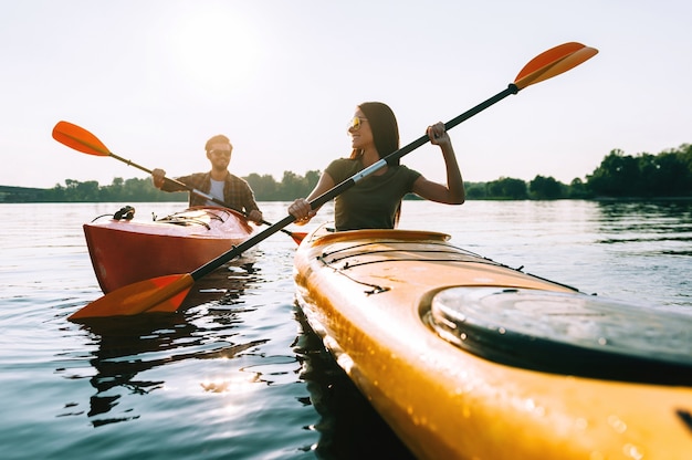 Buen día en el lago. Hermosa joven pareja en kayak en el lago juntos y sonriendo