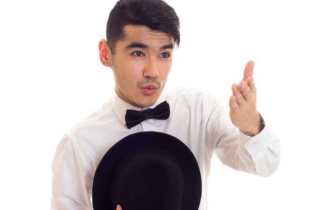 Buen hombre de camisa blanca con pajarita negra y sombrero negro sobre fondo blanco en el estudio