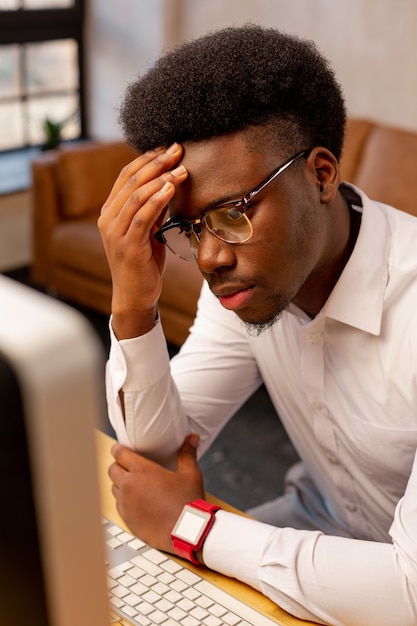 Buen hombre cansado sosteniendo su frente mientras siente la necesidad en el descanso del trabajo