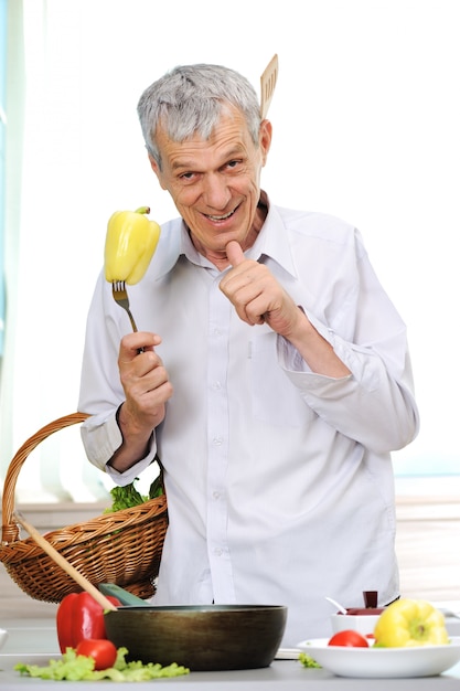 Buen hombre envejecido que cocina en cocina