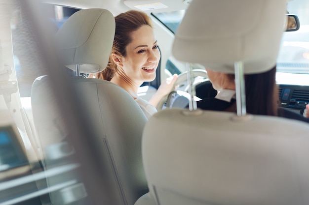 Buen humor. Mujeres atractivas felices alegres que viajan en el coche y se ríen mientras están de buen humor