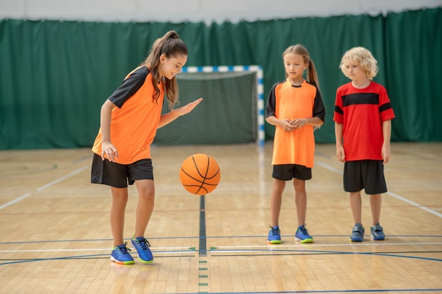 Buen jugador. Una niña jugando con una pelota y mirando disfrutado.