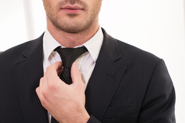 Foto buen negocio. imagen recortada de joven en ropa formal ajustando su corbata