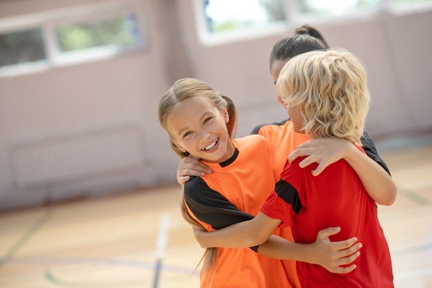 Buen resultado. Niños en ropa deportiva brillante abrazándose y sintiéndose felices