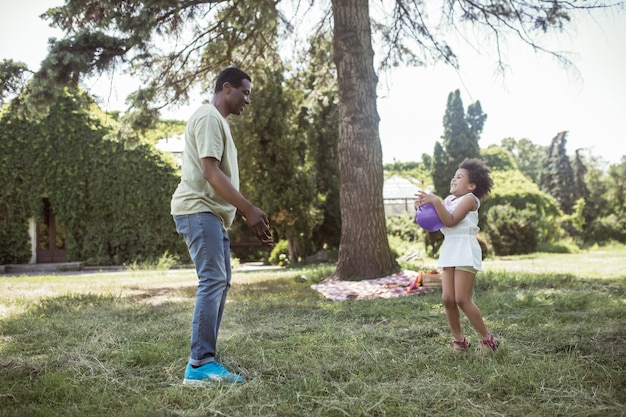 Buen tiempo. hombre y su lindo niño jugando a la pelota en el parque