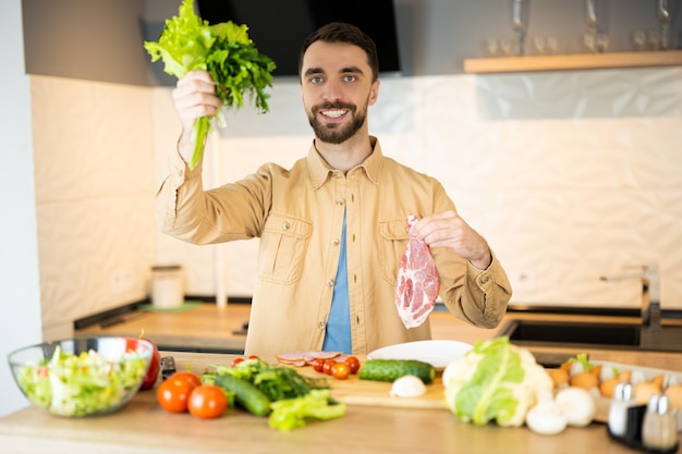 Un buen tipo con una bonita sonrisa está demostrando que prefiere las verduras a la carne para salvar animales. Parece saludable y feliz siendo vegetariano.