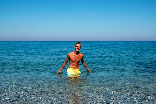 Foto buen tipo con prensa sexual sonriendo en el mar. vacaciones en el mar. hora de verano