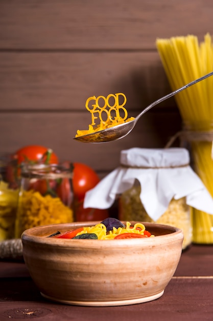 La buena comida está forrada con pasta en una cuchara cerca de un plato.