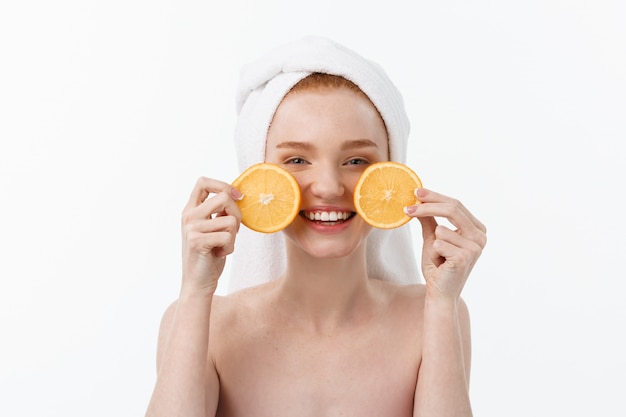 Buena comida para un estilo de vida saludable. Mujer descamisada joven hermosa que lleva a cabo el pedazo de naranja que se opone a.