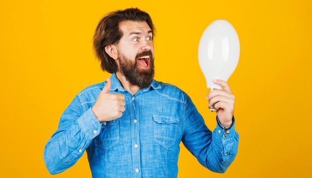 Buena idea hombre barbudo feliz con bombilla que muestra los pulgares hacia arriba inspiración creatividad innovación