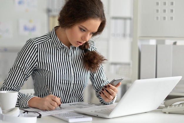 Buena mujer de negocios sentada en la mesa con una laptop