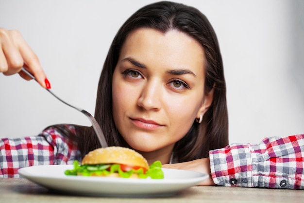 Buena mujer quiere comer hamburguesa dañina.