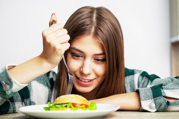 Buena mujer quiere comer hamburguesa dañina