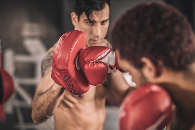 Buena patada. Dos kickboxers trabajando en patadas en un gimnasio