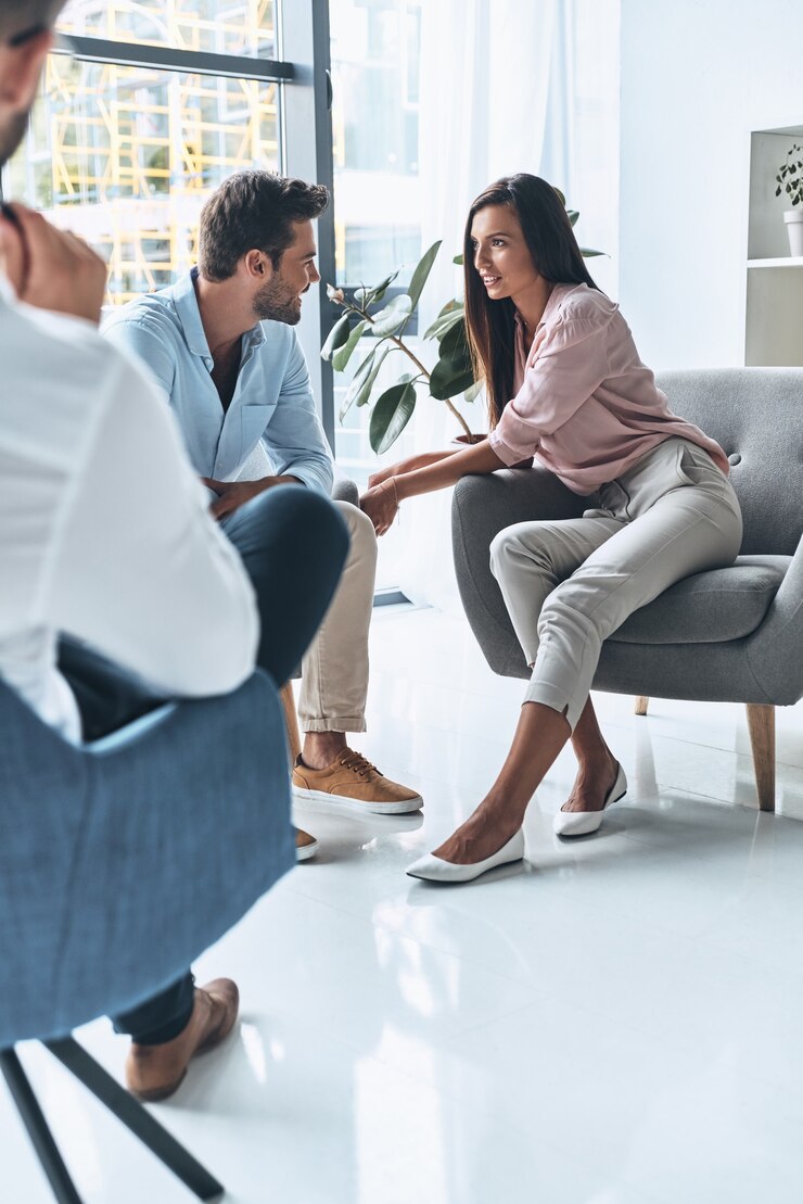 Buena sesion. Pareja de casados jóvenes hablando y sonriendo mientras está sentado en la sesión de terapia