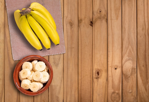 Bündel Bananen und geschnittene Bananen auf Holztisch