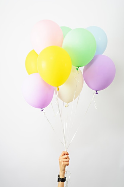 Bündel bunte Heliumballons in der Hand auf festliche Stimmung des weißen Hintergrundes