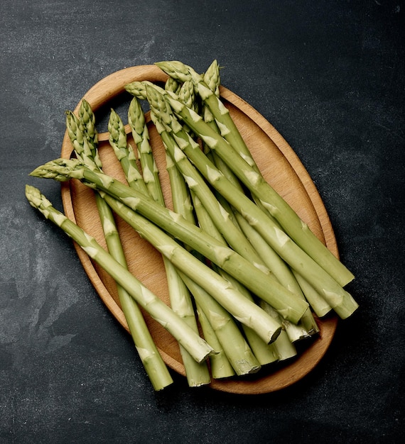 Bündel frischer roher Spargel auf einem hölzernen schwarzen Küchenbrett ein gesundes Produkt