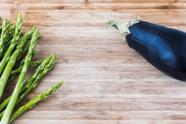 Bündel grüner Spargel auf hölzernem Brett mit Aubergine andcopy Raum