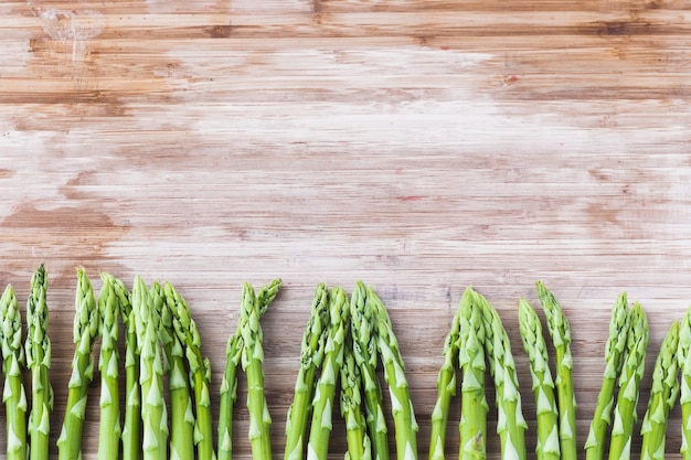 Bündel grüner Spargel auf hölzernem Brett mit Kopienraum