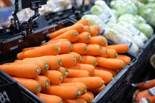 Bündel Karotten Viele orangefarbene Karotten, die auf einem schwarzen Regal im Supermarkt in der Lebensmittelzone aus landwirtschaftlichen Produkten in der Seitenansicht des Kaufhauses platziert sind