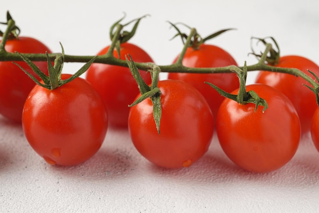 Bündel rote Kirschtomaten mit grünen Blättern auf hellem Hintergrund