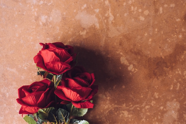 Bündel rote Rosen auf braunem Schmutzbretthintergrund. Freier Platz für Text