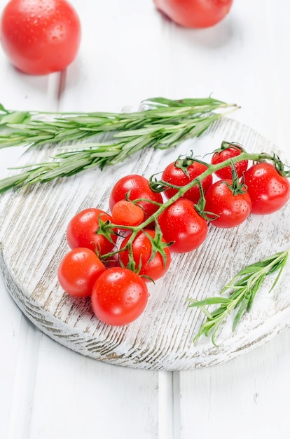 Bündel saftiger Bio-Rotkirschtomaten mit grünem Rosmarin, Knoblauch und Gewürzen