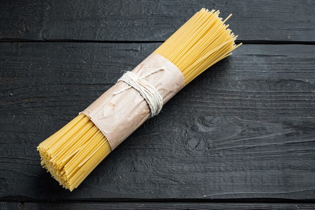 Bündel Spaghetti, rohes italienisches Nudelset, auf schwarzem Holztisch